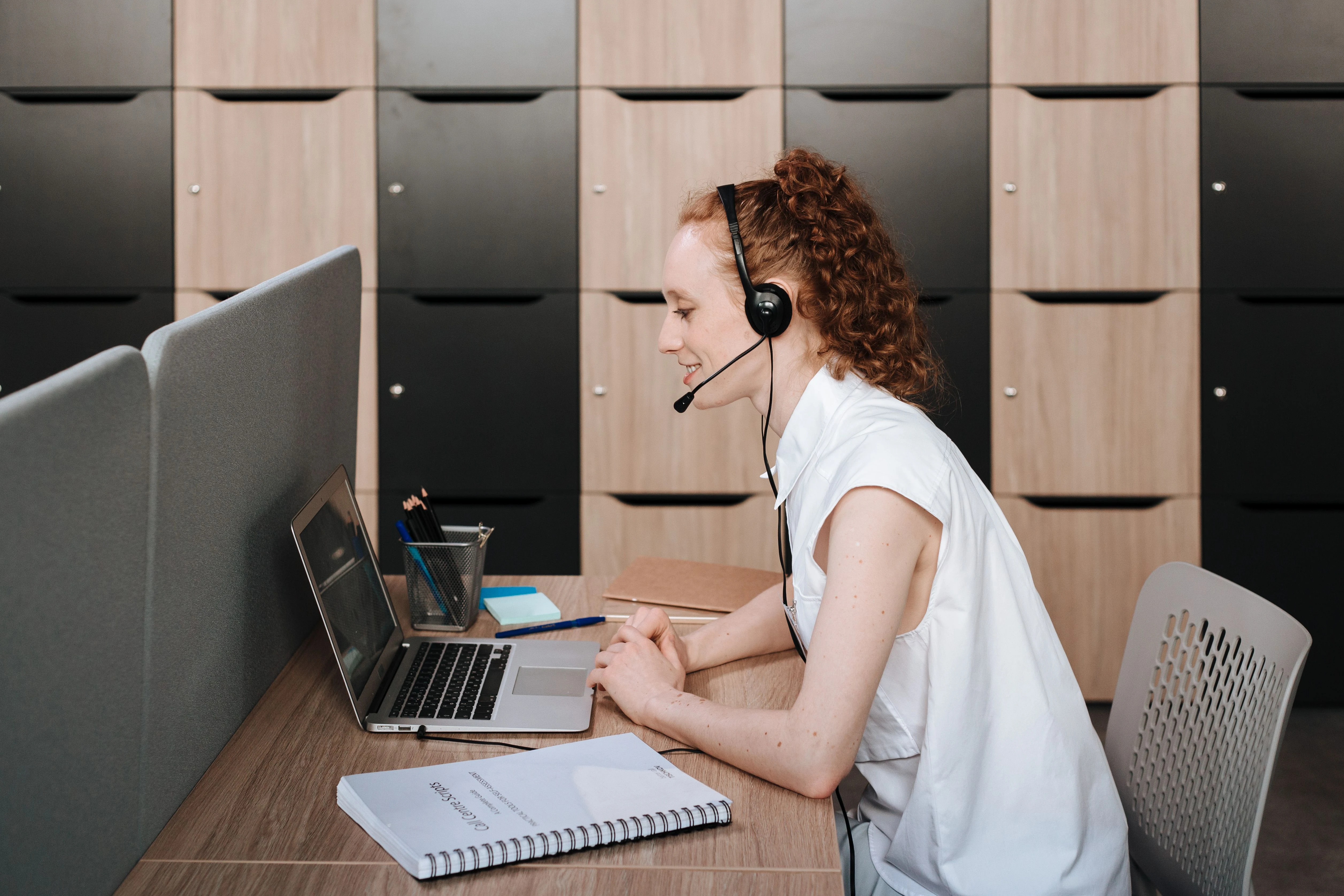 An office worker wearing a headset while using a laptop.
